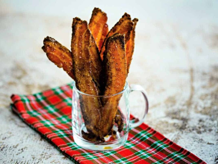 slices of sugared pepper bacon in a clear glass mug