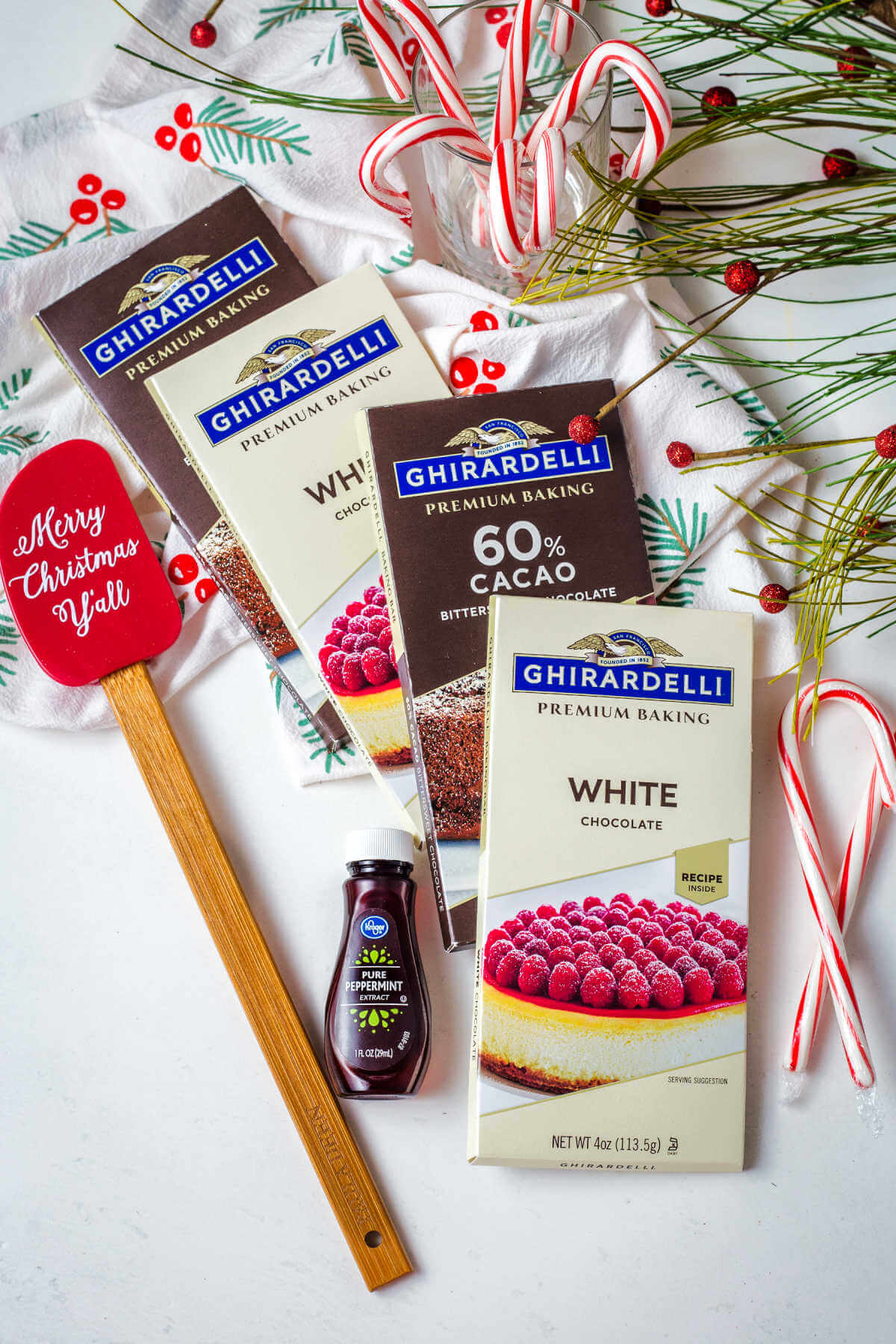 Ghiradelli baking bars and peppermint extract on a table with candy canes.