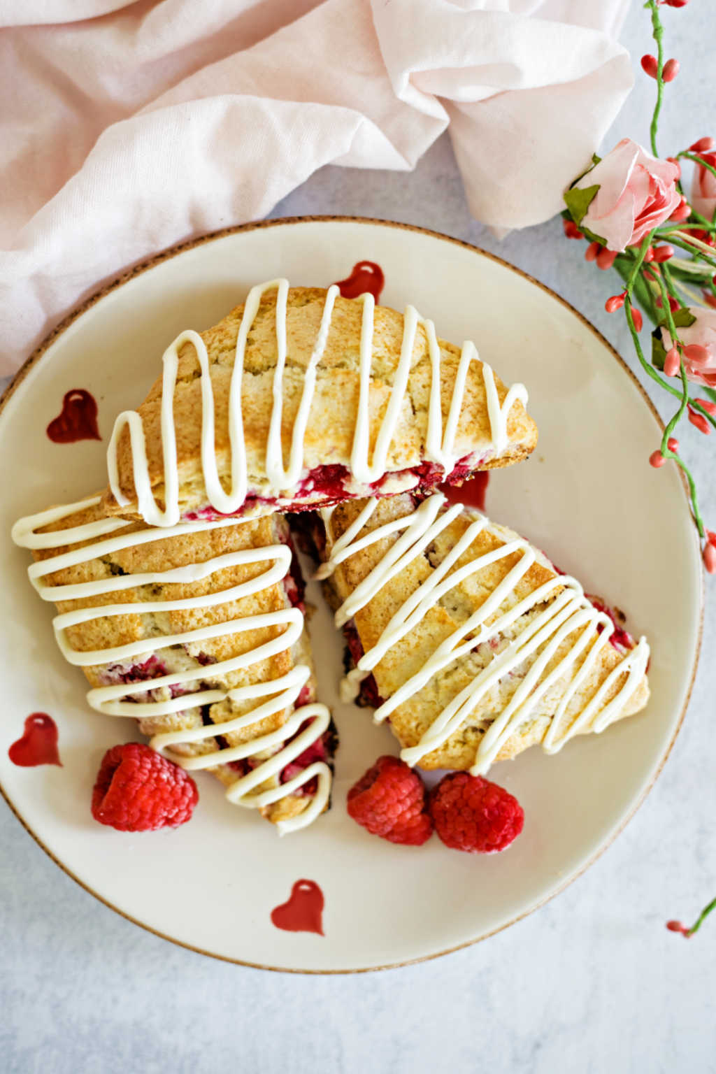 raspberry scones on a Valentine heart plate with roses o a table