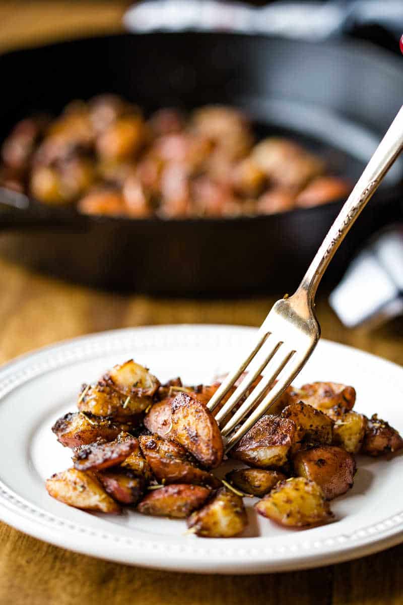 roasted red potatoes on a white plate with fork