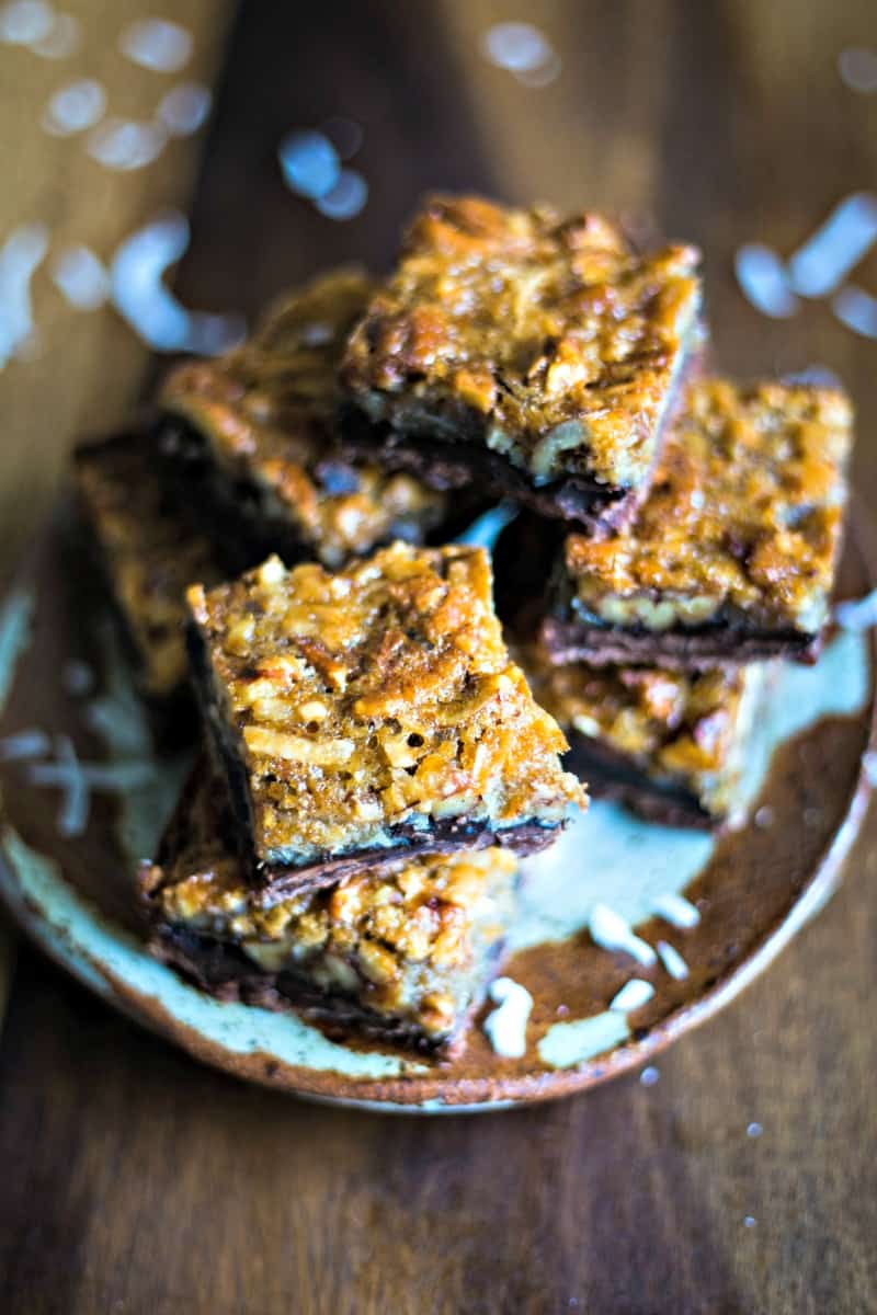 a stack of coconut pecan pie bars on a stone plate