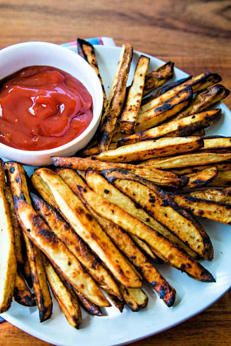 a plate of grilled french fries with a bowl of spicy ketchup dip