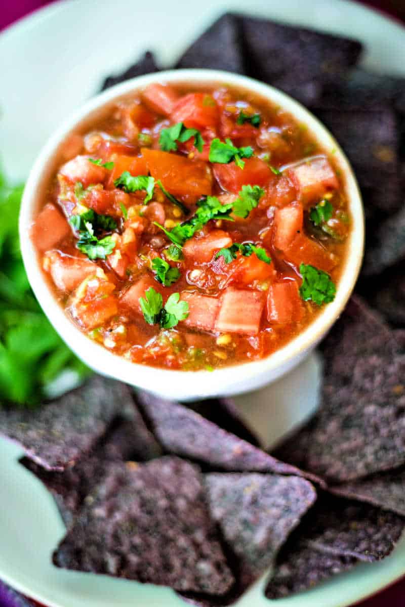 fresh tomato salsa on a platter with blue corn tortilla chips