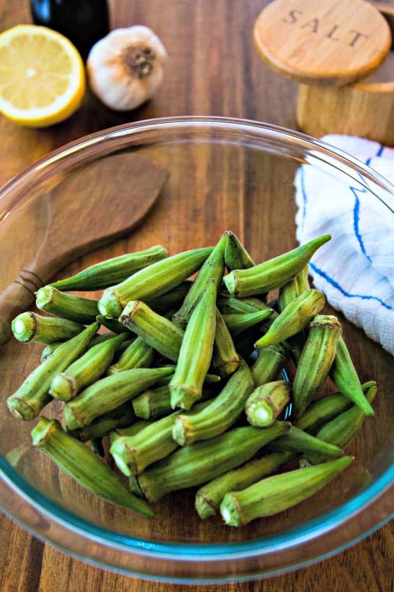 a glass bowl of raw okra pods