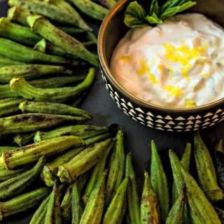 whole okra with char marks on a plate with a lemon dipping sauce