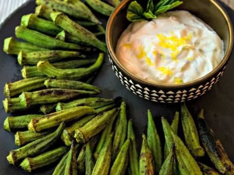 whole okra with char marks on a plate with a lemon dipping sauce