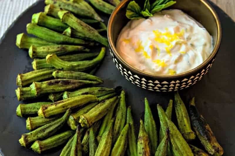 whole okra with char marks on a plate with a lemon dipping sauce