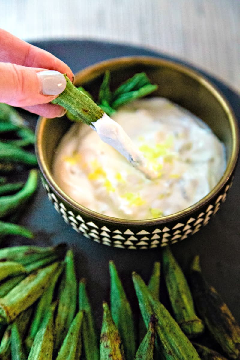 dipping okra in a bowl of lemon basil greek yogurt