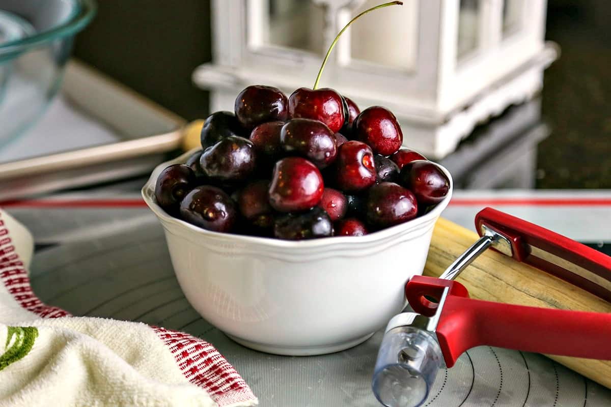 a bowl of cherries and a cherry pitter