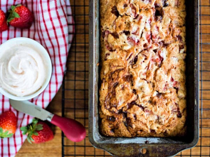 a loaf of strawberry bread with fresh strawberries and a bowl of strawberry butter