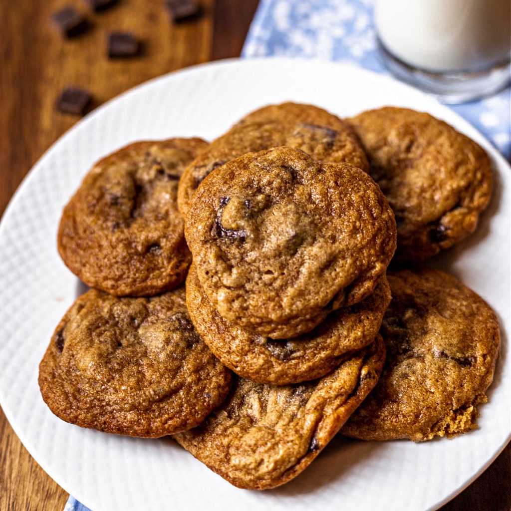 chocolate chunk cookies on a white plate on a wooden table.