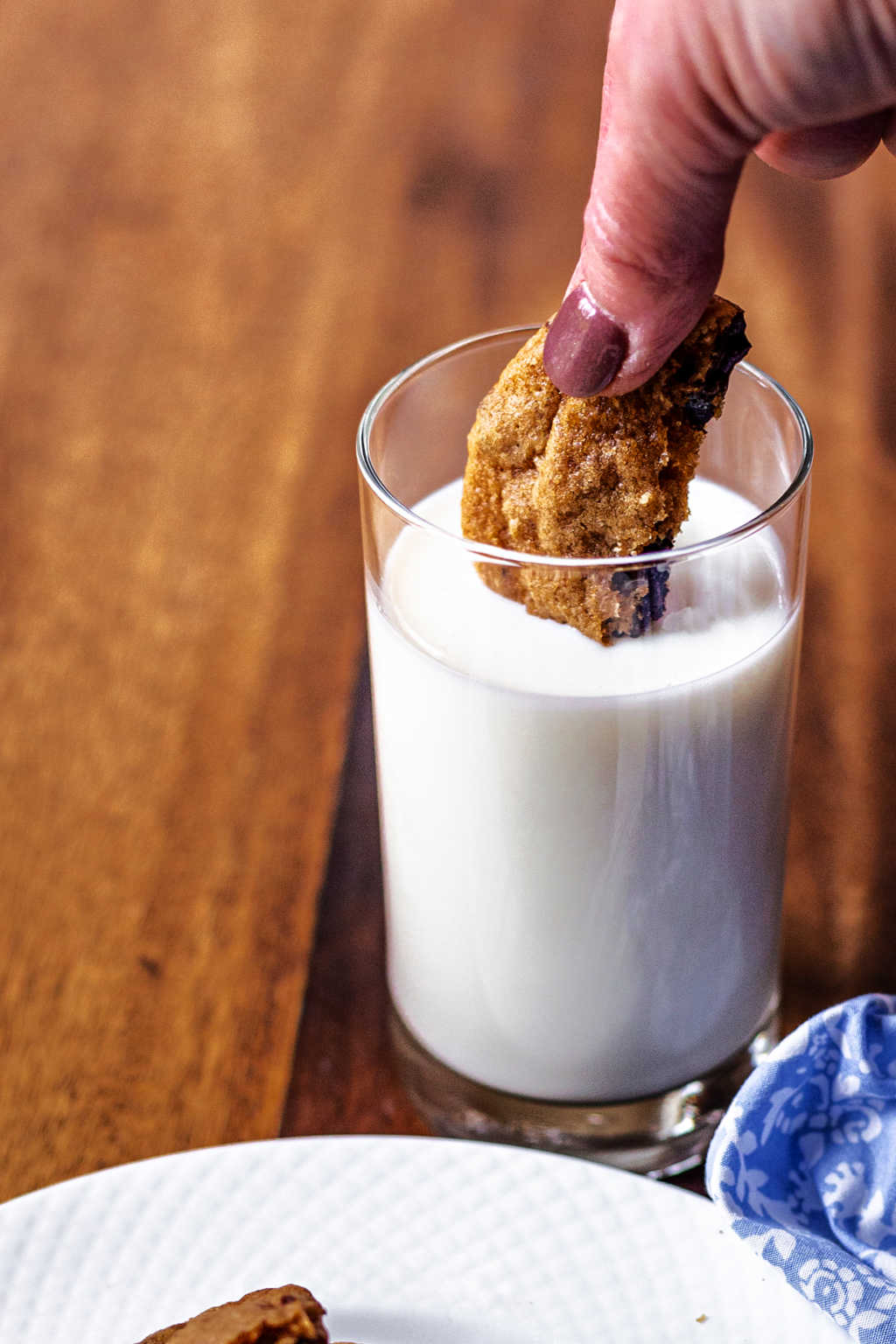 dunking a chocolate chunk cookie in a glass of milk.