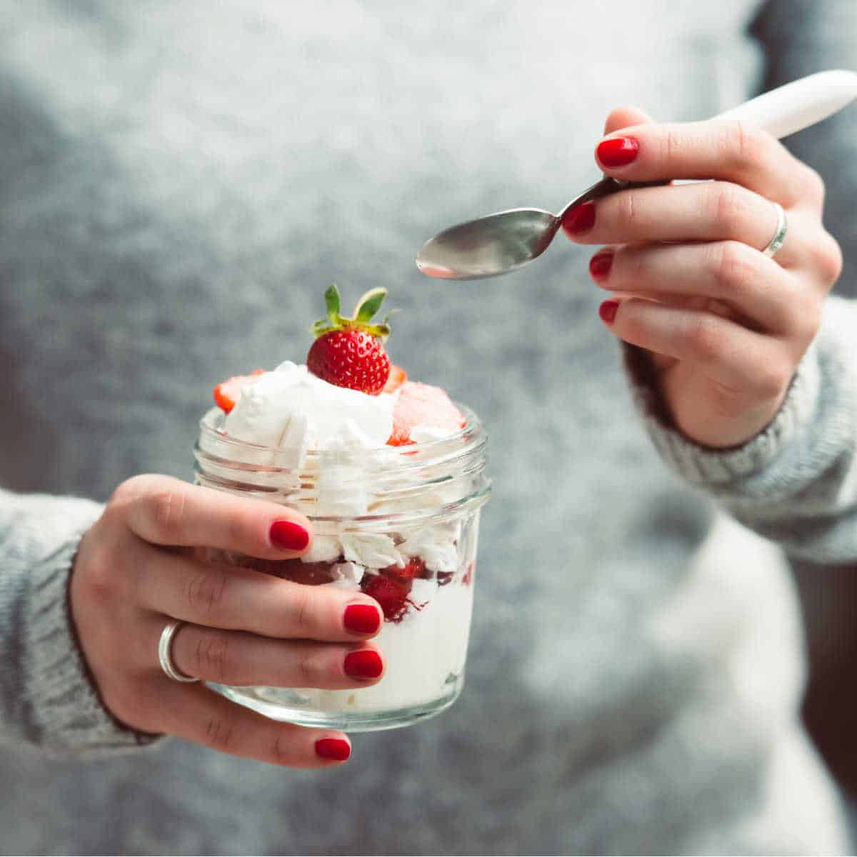 close up image of hands holding a mason jar dessert