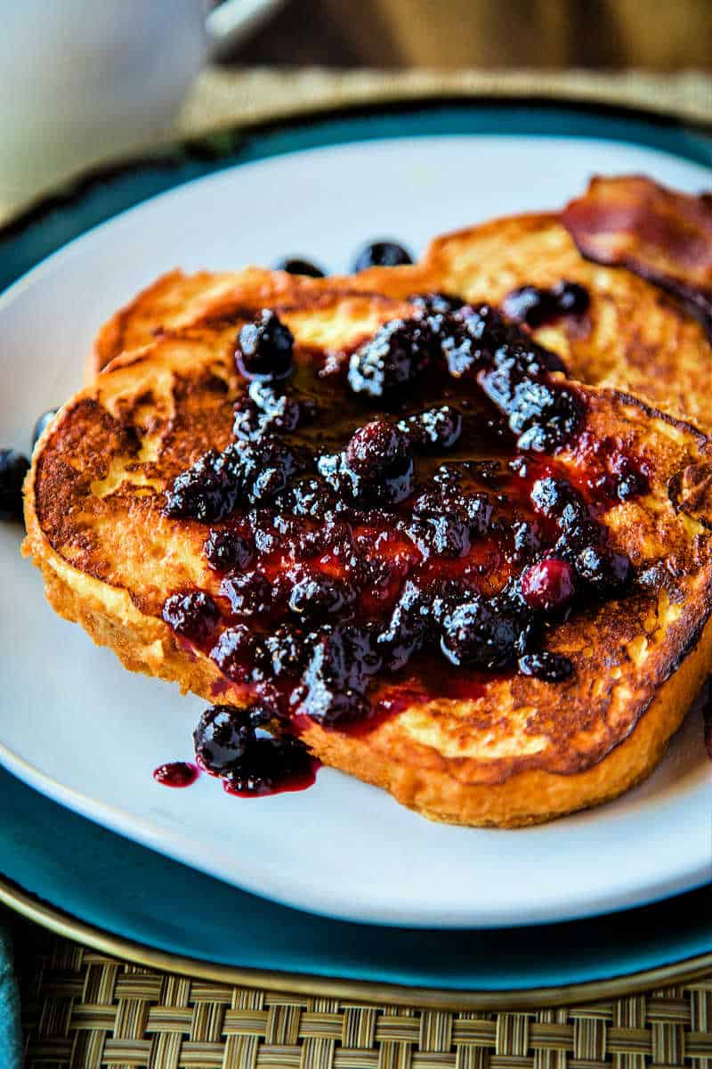 two slices of french toast on a white plate with a blueberry compote