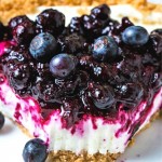 a slice of no bake blueberry cheesecake with a bite missing on a white plate.