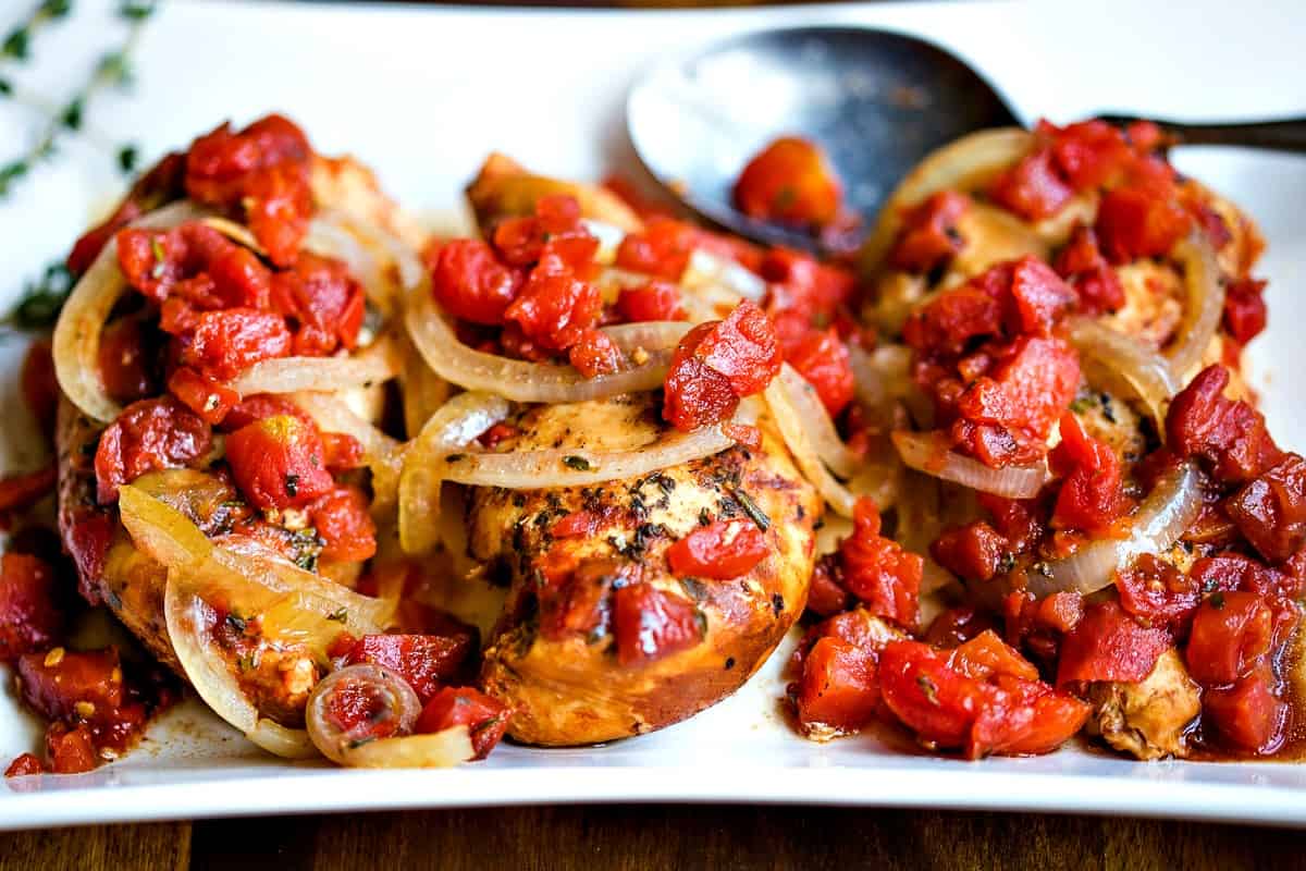 Slow Cooker Balsamic Chicken with onions and tomatoes on a white platter