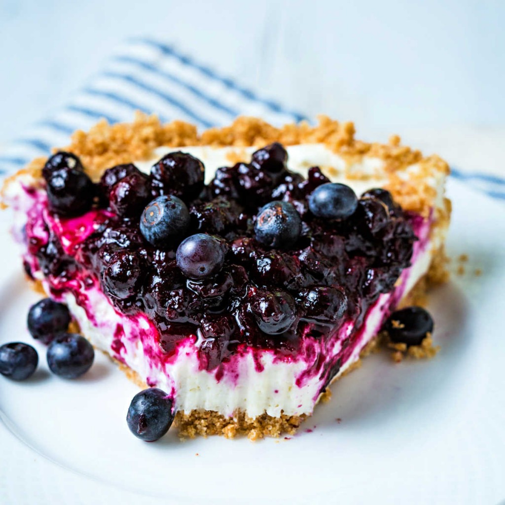 a slice of no bake blueberry cheesecake with a bite missing on a white plate.
