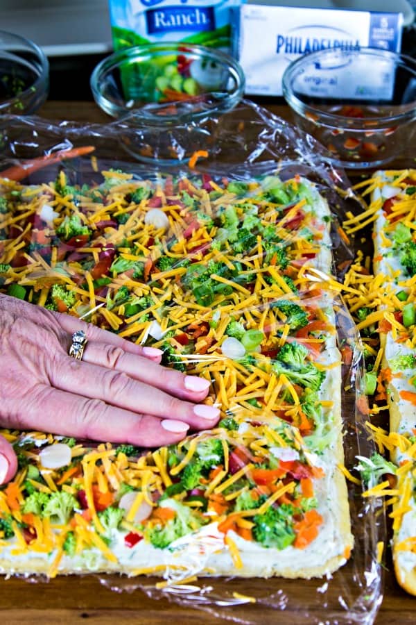 Use plastic wrap to press veggies into the cream cheese on cool veggie pizza