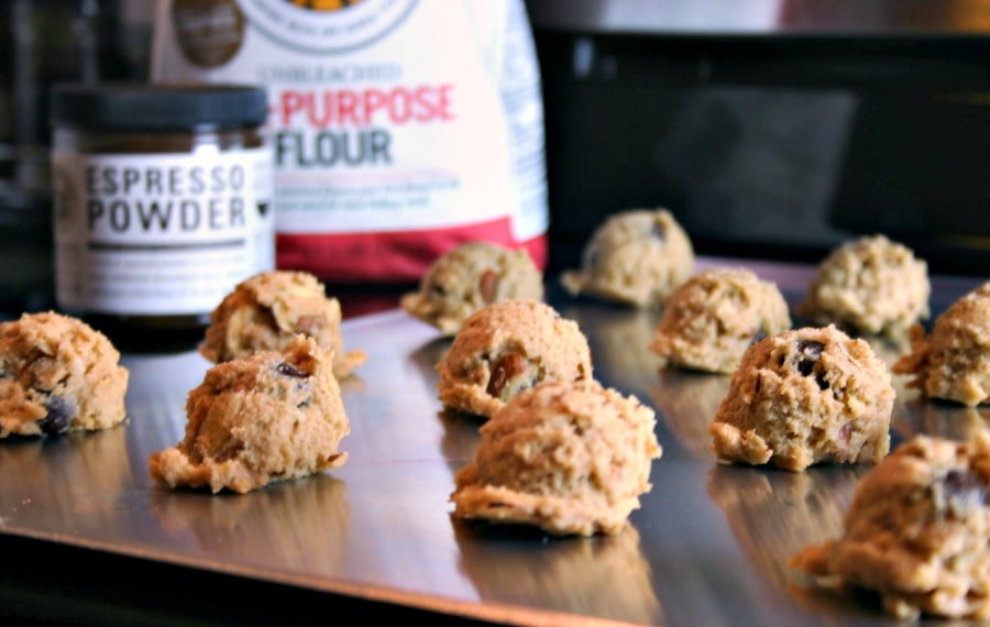 A close up of cookie dough balls on a baking sheet