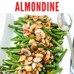 Green beans almondine on a white platter topped with almonds and mushrooms.