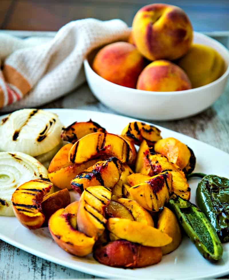 grilled peaches, onions, and jalapenos on a white platter
