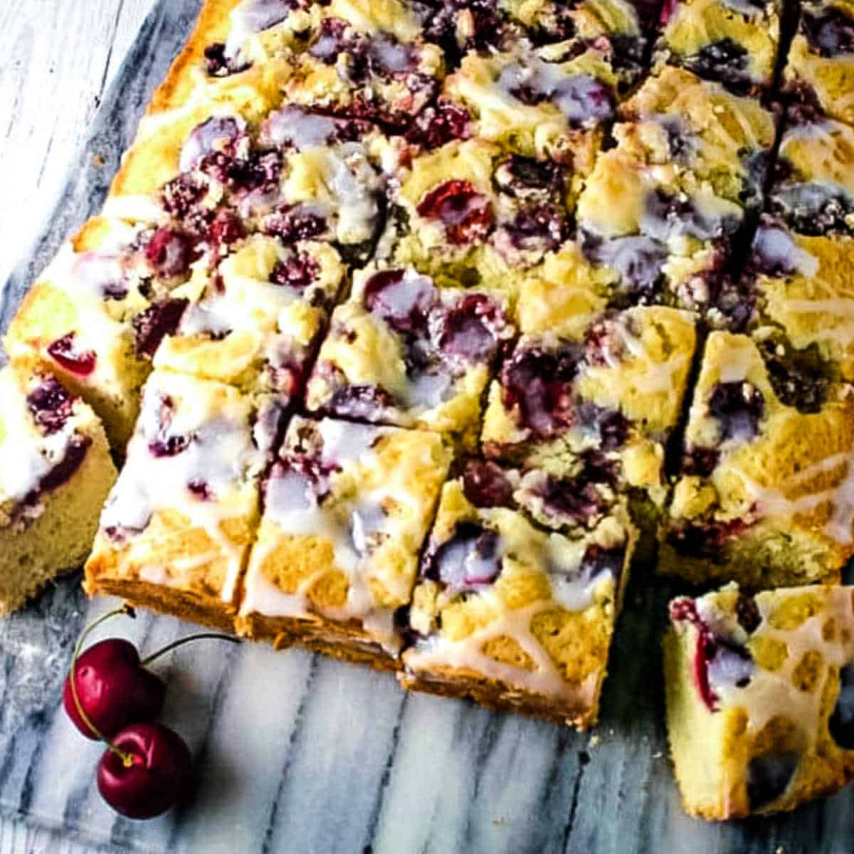 cherry cake cut into squares on a marble board