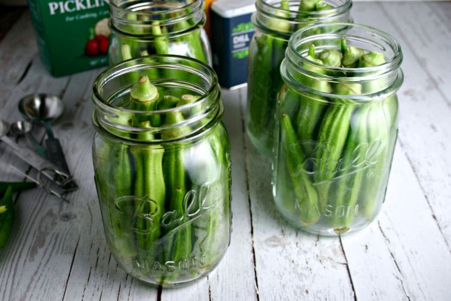 A group of pint jars filled with okra pods on a table