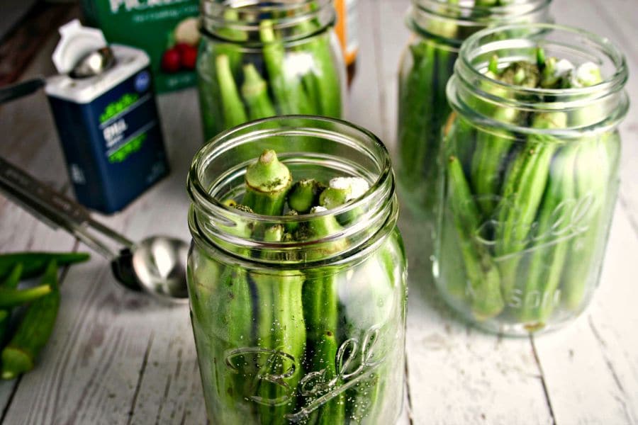 A close up of a pint jar filled with okra pods