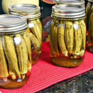 A group of pint jars on a table, with Pickled Okra