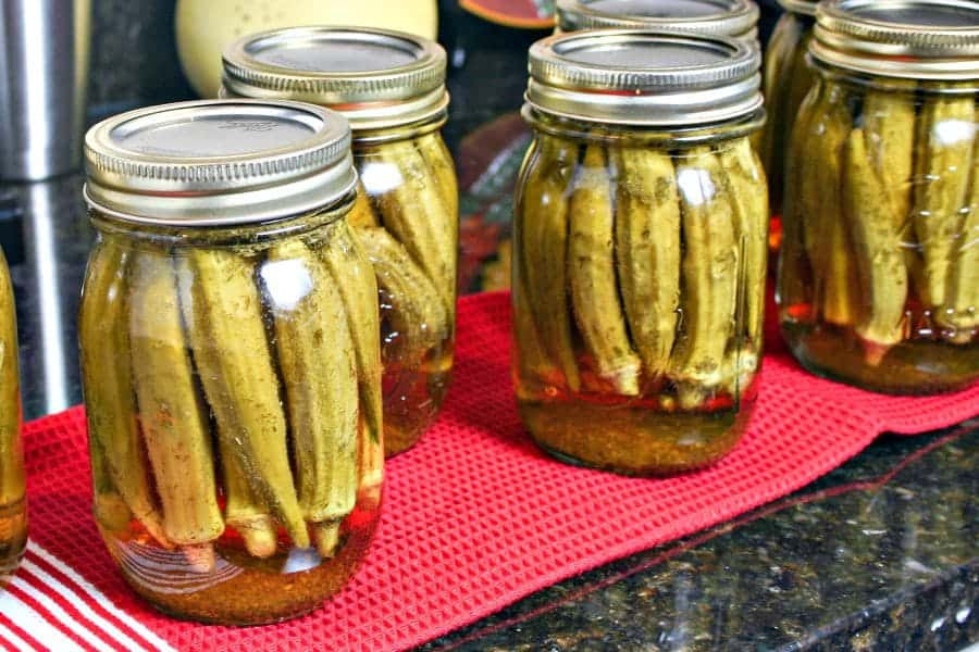 A group of pint jars on a table, with Pickled Okra 