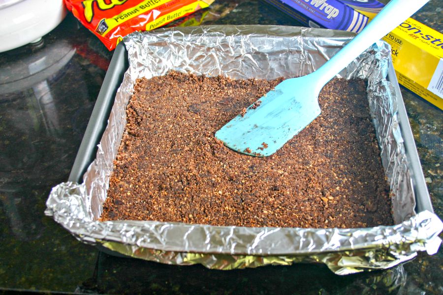 A pan lined with aluminum foil with a chocolate crust