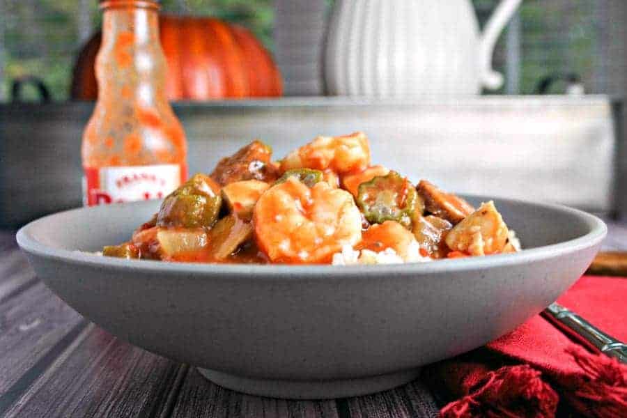 A bowl of food on a table, with Chicken, Sausage, and Shrimp Gumbo