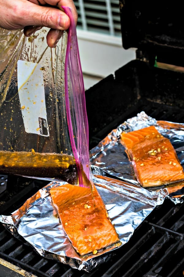 Cooking salmon filets on the grill in aluminum foil boats with marinade