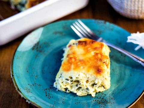A serving of spinach spaghetti squash casserole on a blue plate with a fork