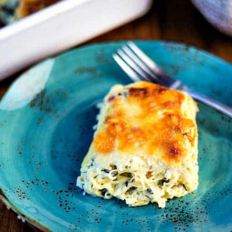 A serving of spinach spaghetti squash casserole on a blue plate with a fork