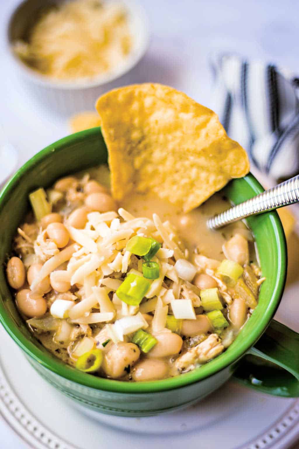 white chicken chili in a green soup bowl with a tortilla chip