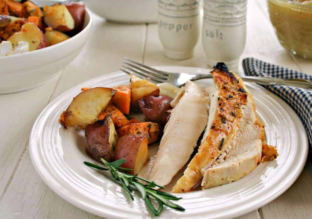 A plate of food on a table, with Rotisserie chicken and roasted vegetables