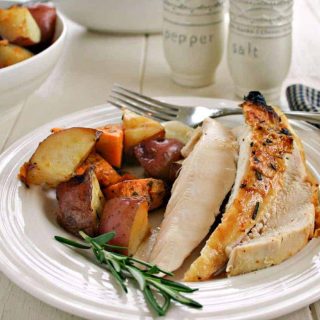 A plate of food on a table, with Rotisserie chicken and roasted vegetables