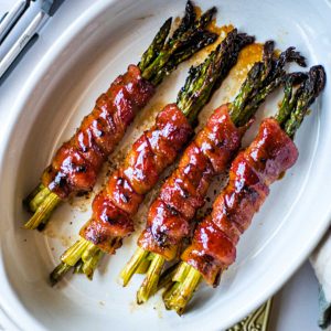 bacon wrapped asparagus bundles in a white baking dish