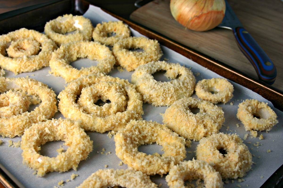 A close up of food on a baking sheet, with Crispy Oven Baked Onion Rings