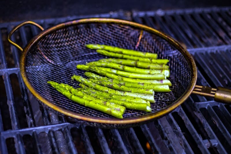 asparagus spears in a grill basket on a gas grill