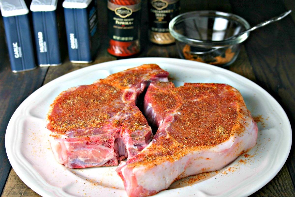 Two pork chops with spice rub a on a plate, with Easy Magic Rub for Grilled Chops