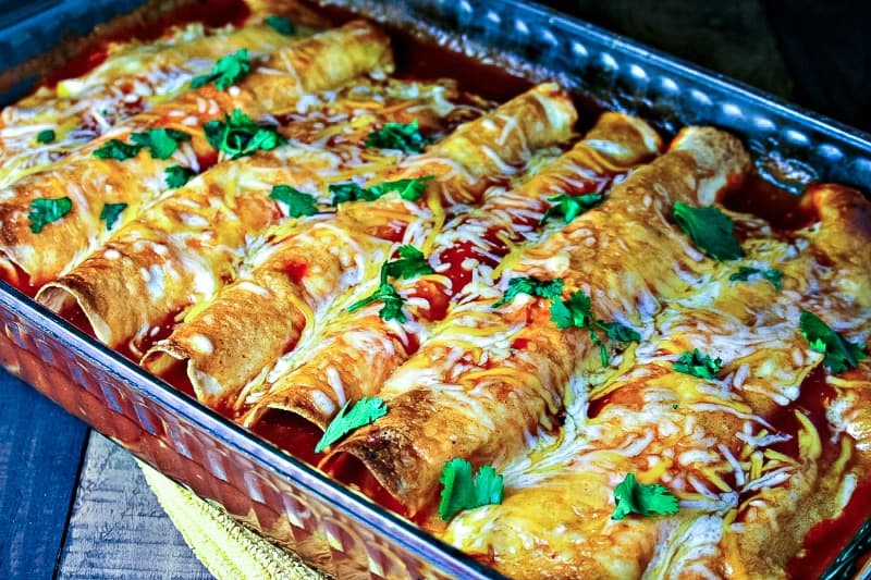 A baking dish sitting on top of a table, with Chicken and Cheese Enchiladas