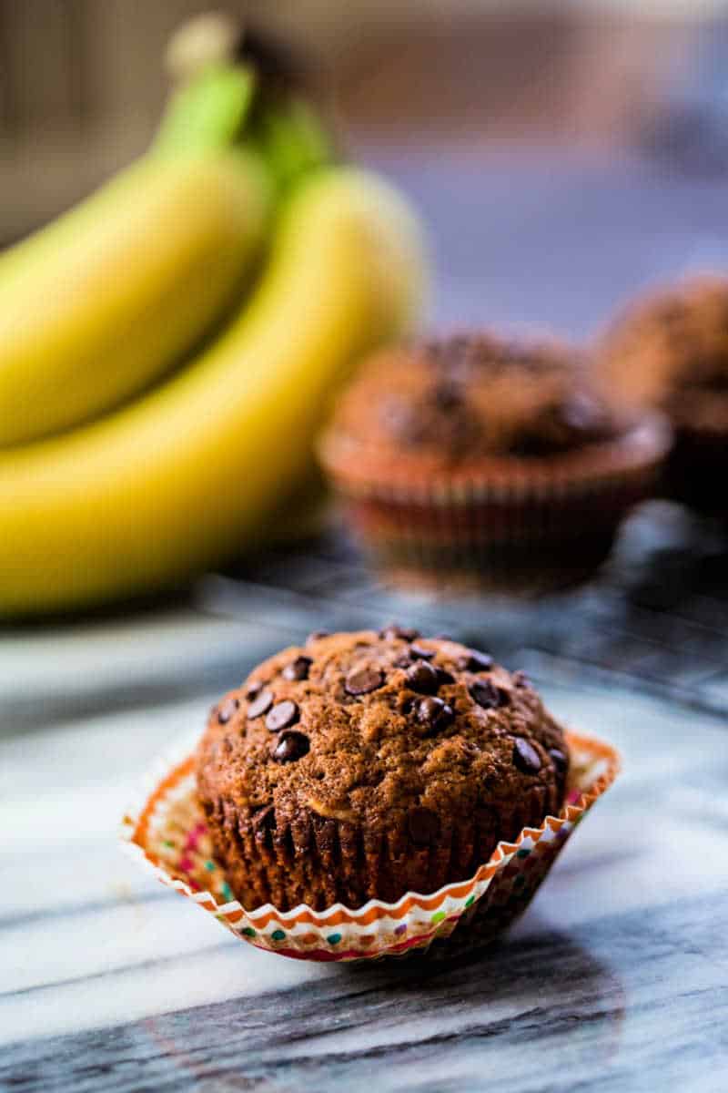 a chocolate banana muffin on a marble counter with the paper lining peeled off