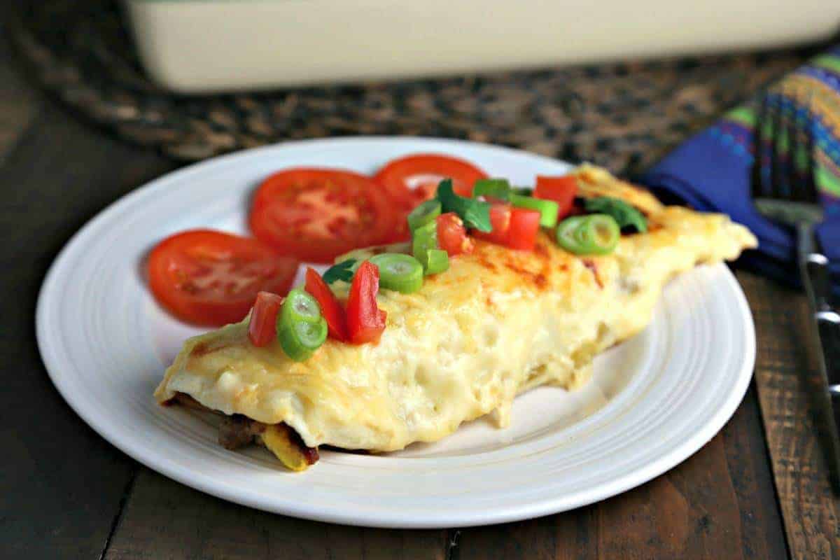 A plate of food on a table, with breakfast enchiladas