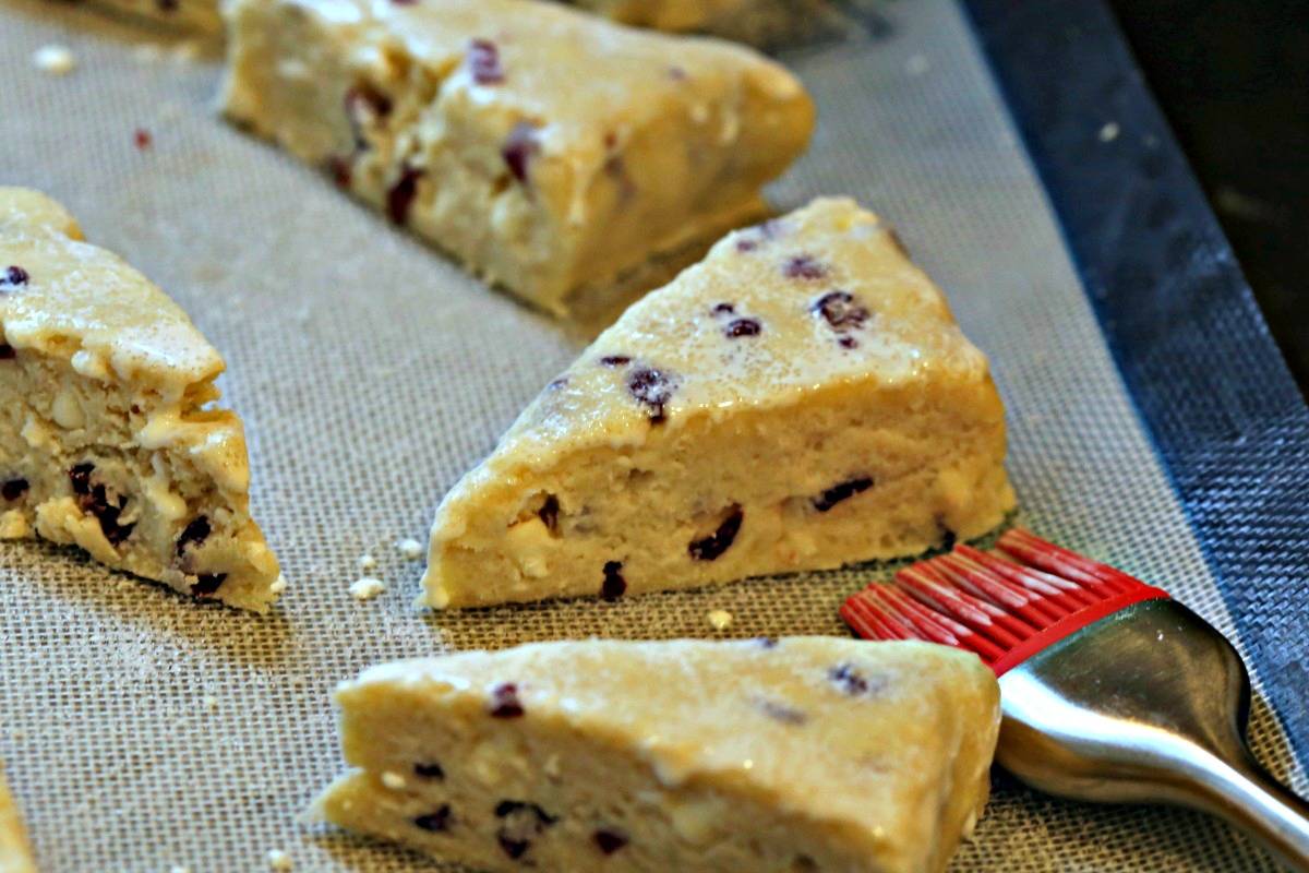 Cutting White Chocolate Cranberry Scones into triangles on a pastry board