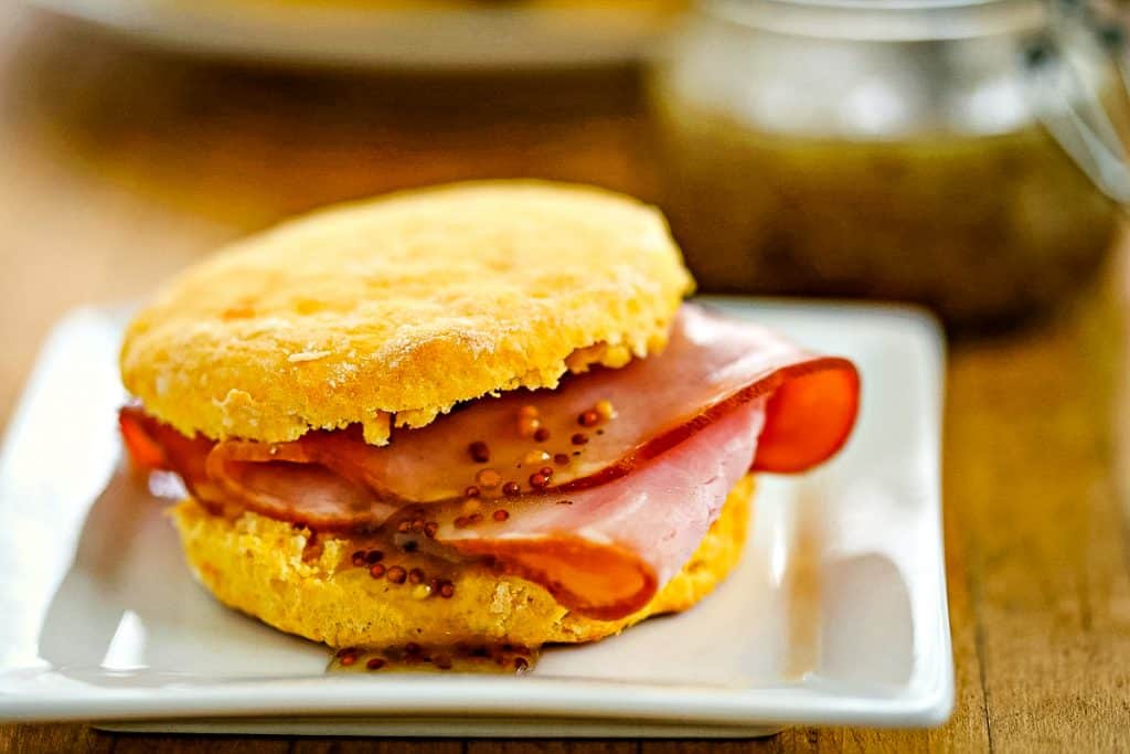 Buttery Sweet Potato Biscuit with ham and mustard vinaigrette on a white plate