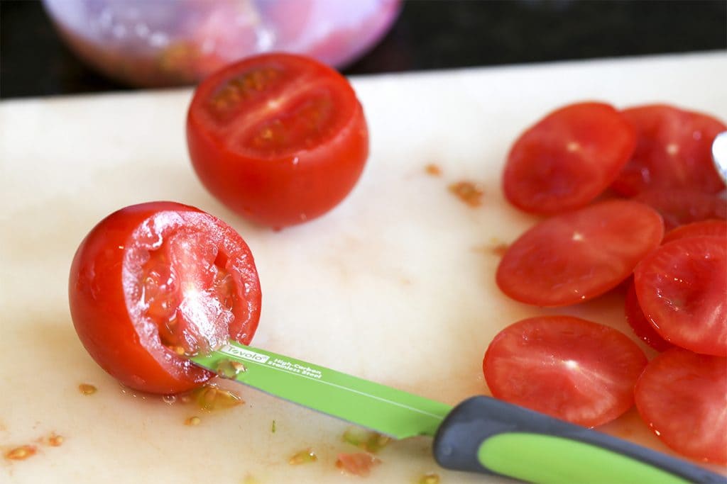 cherry tomatoes on a cutting board with a knife