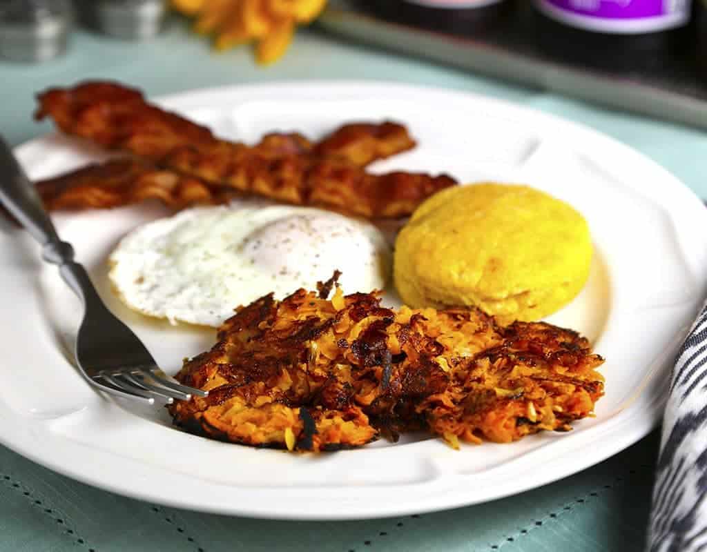 A plate of food with a fork, with fried egg, biscuit, and Sweet Potato Hash Browns
