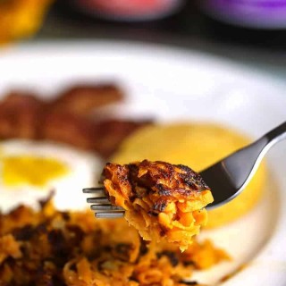 A close up of a plate of food with a fork, with Sweet Potato Hash Browns